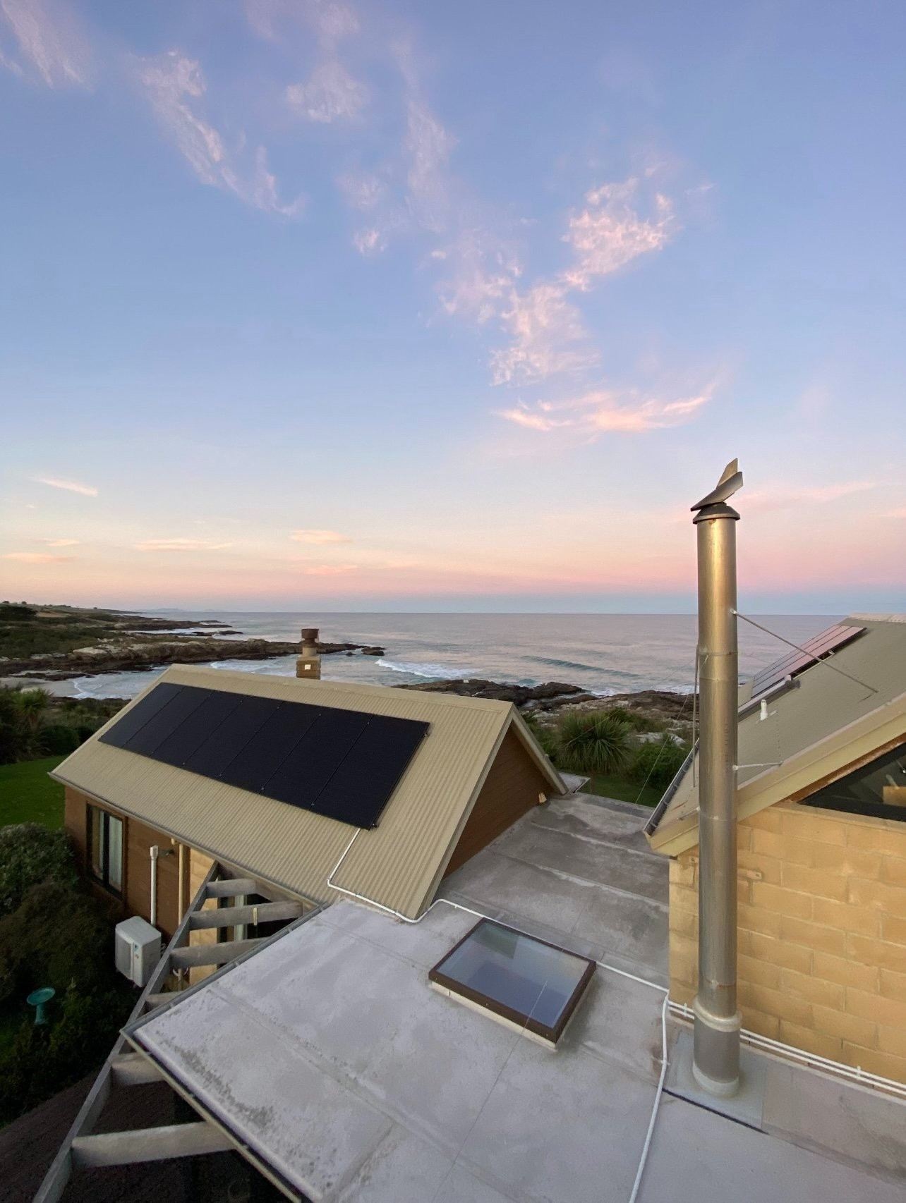 Black solar array on a coastal home at dusk