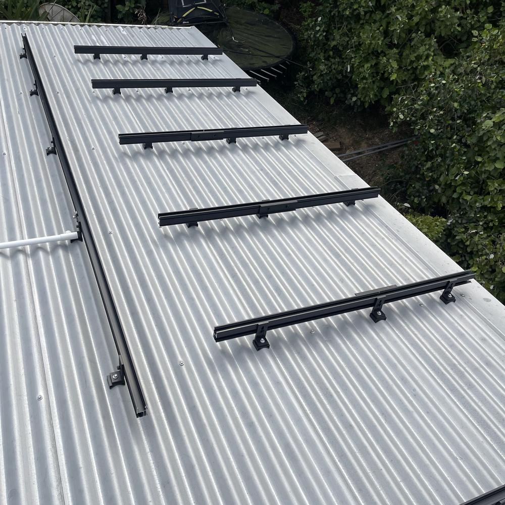 Black mounting rails fixed across a silver corrugated roof, ready for panels